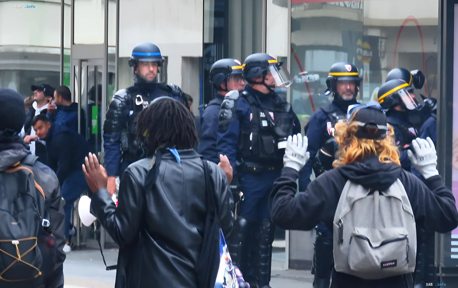 Французская полиция в защитном снаряжении перед протестующими с поднятыми руками во время беспорядков