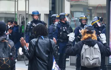 Французская полиция в защитном снаряжении перед протестующими с поднятыми руками во время беспорядков