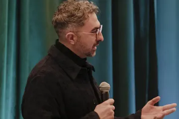 Мустафа Сулейман выступает с микрофоном на конференции по искусственному интеллекту