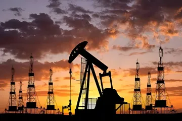 Silhouettes of oil pumps and drilling rigs against a sunset sky