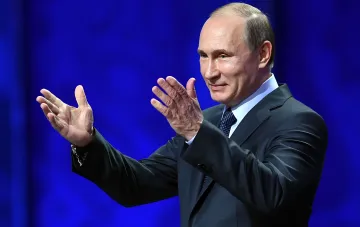 Президент России Владимир Путин выступает на сцене с жестикуляцией руками