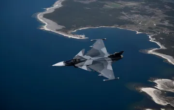 Schwedisches Mehrzweck-Kampfflugzeug JAS 39 Gripen im Flug über einer Küste