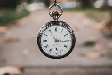 Antike Taschenuhr an einer Kette vor verschwommenem herbstlichen Hintergrund