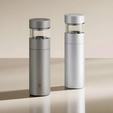 Два сріблястих титанових термоси Xiaomi Mijia зі скляною камерою для заварювання чаю на бежевому тлі