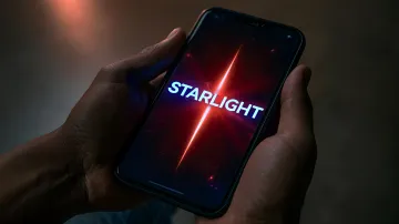Person holding a smartphone displaying the word Starlight on a glowing red screen in the dark