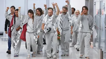 Eine Gruppe freigelassener Aktivisten in grauen Uniformen und Keffiyehs beim Gehen durch einen Flur