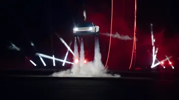 White Tesla Roadster electric sports car hovering in the air amid spotlights and smoke clouds