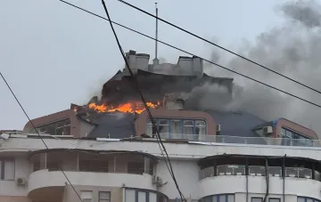 Поврежденная крыша многоэтажного здания в Одессе охвачена огнем и дымом после удара дрона