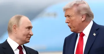 Donald Trump und Wladimir Putin stehen nebeneinander und führen ein Gespräch.