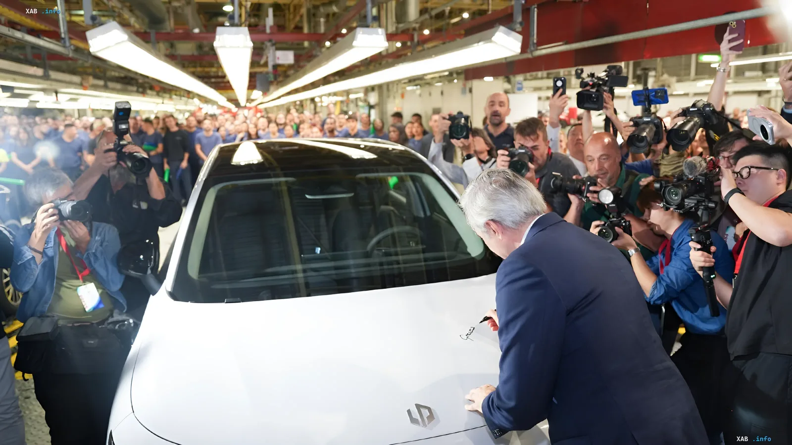 Представитель компании подписывает первый электромобиль Leapmotor B10 на заводе в Сарагосе среди толпы журналистов