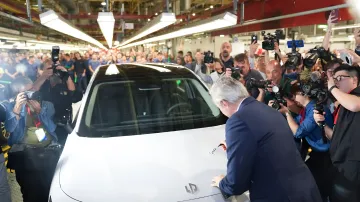 Company representative signing the first Leapmotor B10 electric vehicle at the Zaragoza plant amidst a crowd of journalists