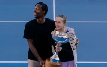 Elina Switolina und Gael Monfils halten einen Tennispokal auf einem blauen Platz