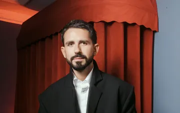 Ukrainian film producer Yevhen Taller in a black jacket and white shirt against a red background