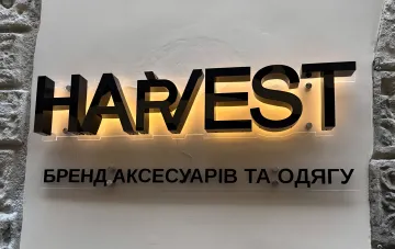 Schwarzes beleuchtetes Schild der Bekleidungs- und Accessoires-Marke Harvest an einer Wand