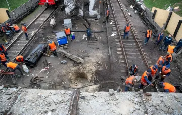 Группа рабочих в оранжевых жилетах устраняет последствия удара на железнодорожных путях в Киеве