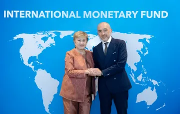 Голова НБУ Андрій Пишный та директорка-розпорядниця МВФ Крісталіна Георгієва тиснуть руки на тлі логотипа МВФ
