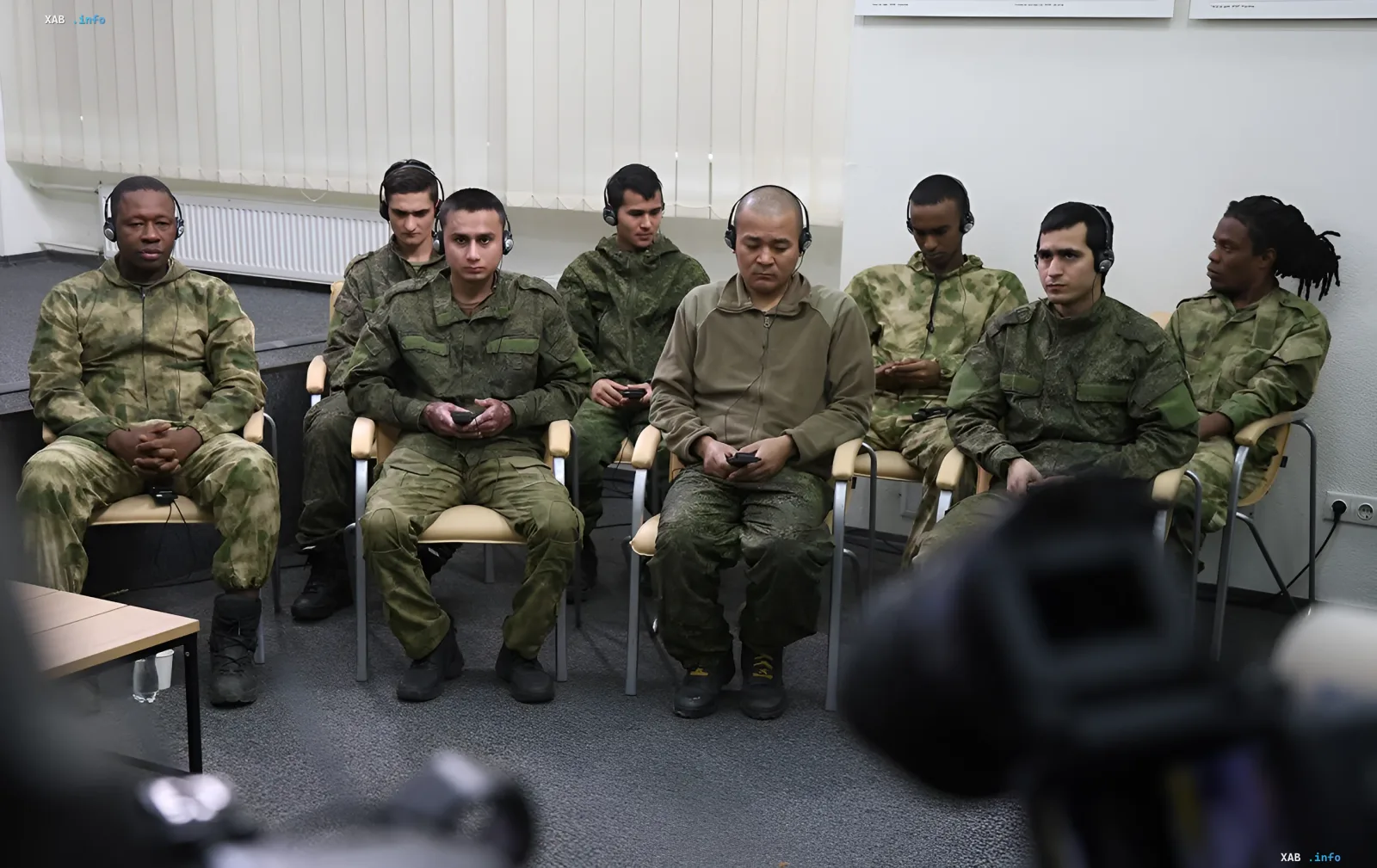 A group of foreign contract soldiers of the Russian army wearing headphones sit indoors during a press conference