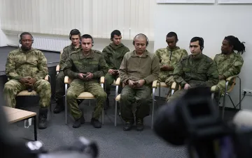 Eine Gruppe ausländischer Vertragssoldaten der russischen Armee mit Kopfhörern sitzt während einer Pressekonferenz in einem Raum