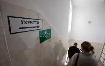 People walking down stairs toward a shelter following directional signs during an air raid alert in Kyiv