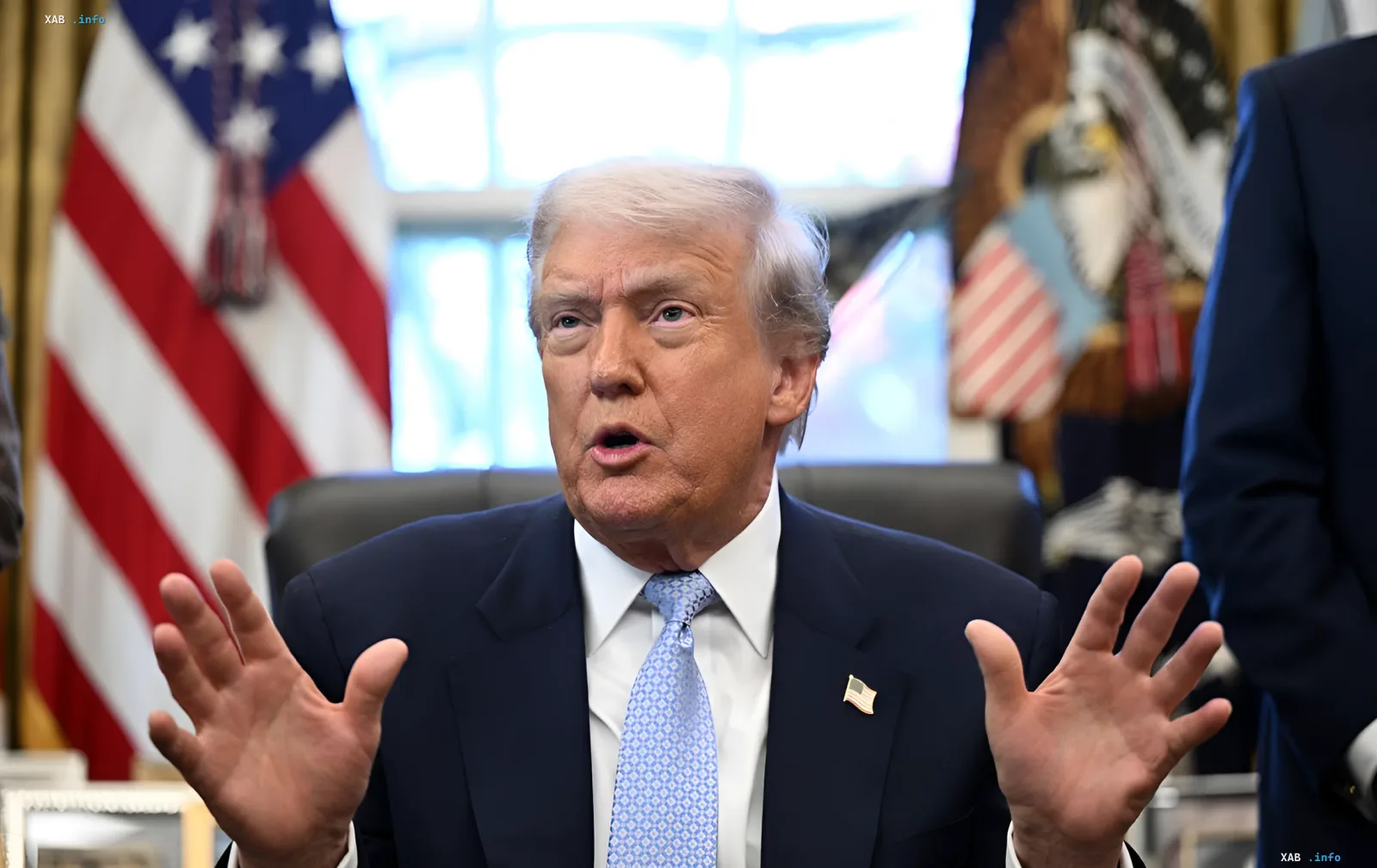Дональд Трамп активно жестикулирует во время выступления в Овальном кабинете на фоне американского флага