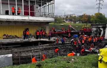 Аварийные бригады и рабочие в оранжевых жилетах проводят восстановительные работы на поврежденной станции метро Черниговская в Киеве