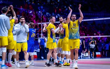 Ukraine men's volleyball team in yellow uniform applauding fans at the arena