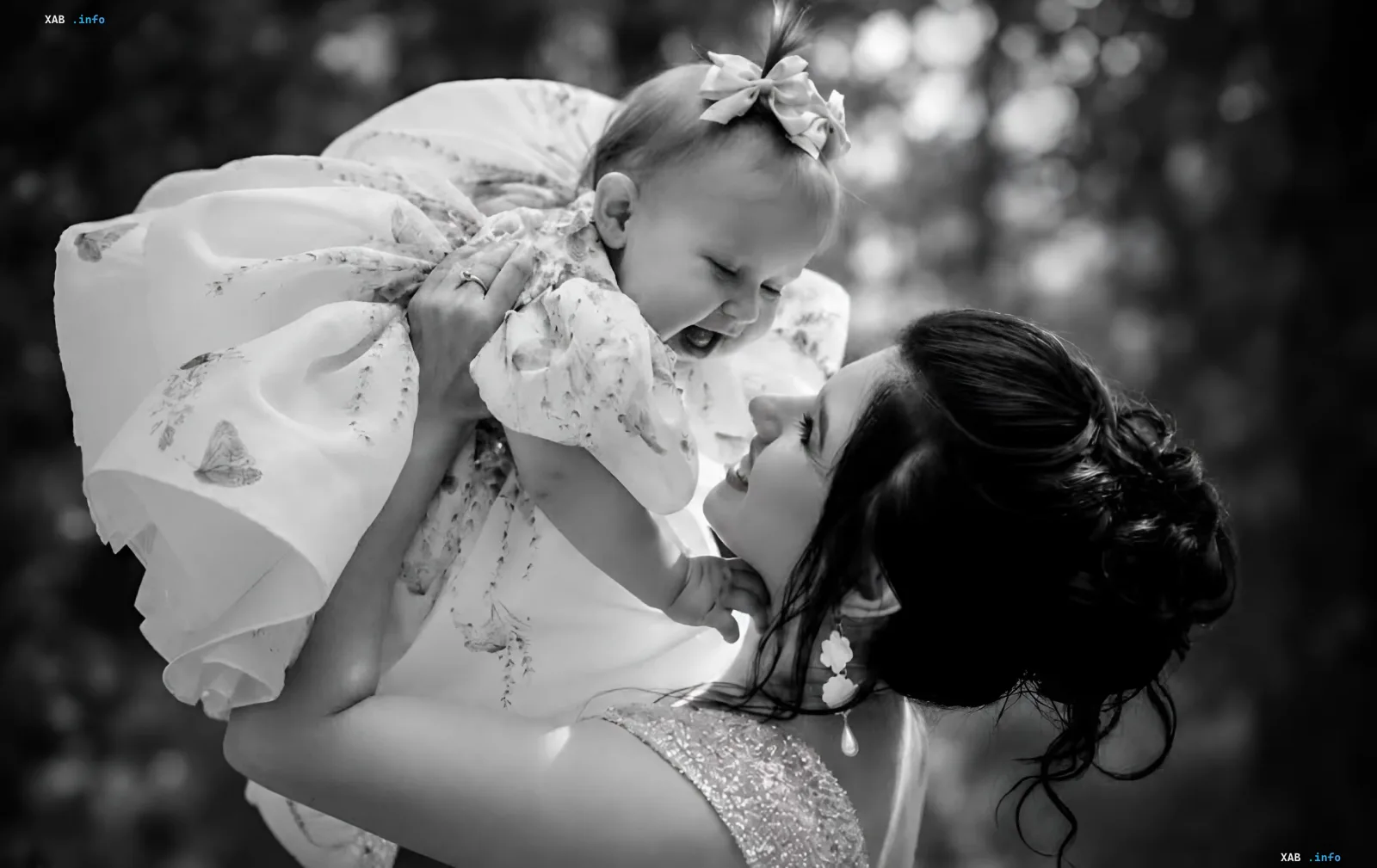 A mother tenderly holding her little daughter in a festive dress outdoors