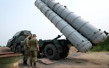 Military personnel near an S-300 surface-to-air missile launcher at a training ground