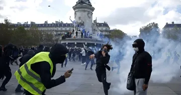 Protesters in masks and yellow vests during clashes near a monument in Paris