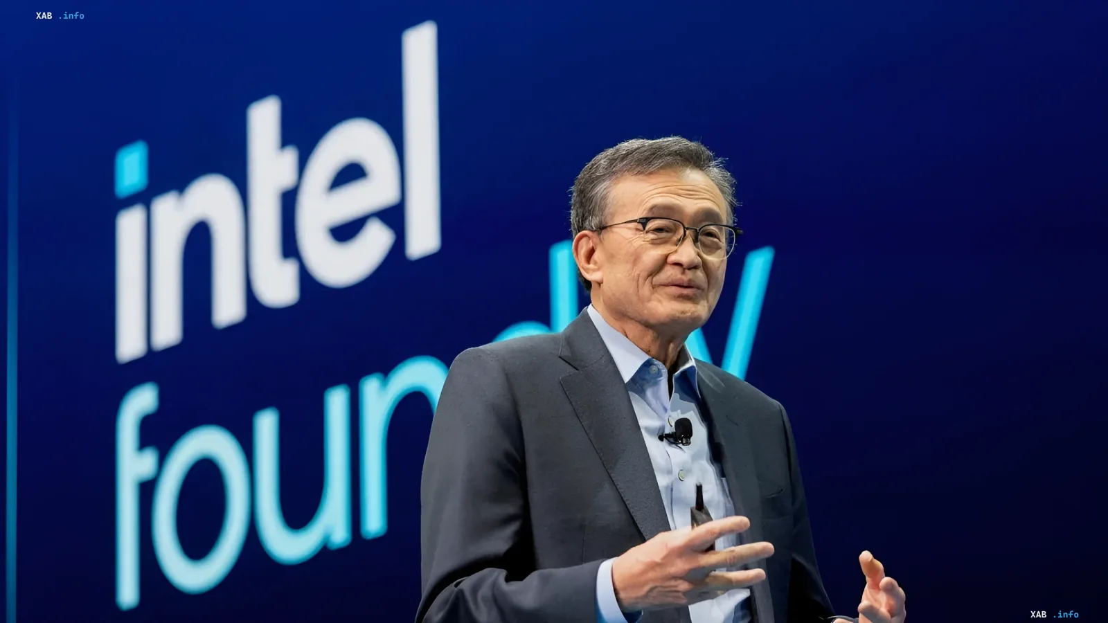 Intel CEO Lip-Bu Tan speaking at a presentation against a blue branded background