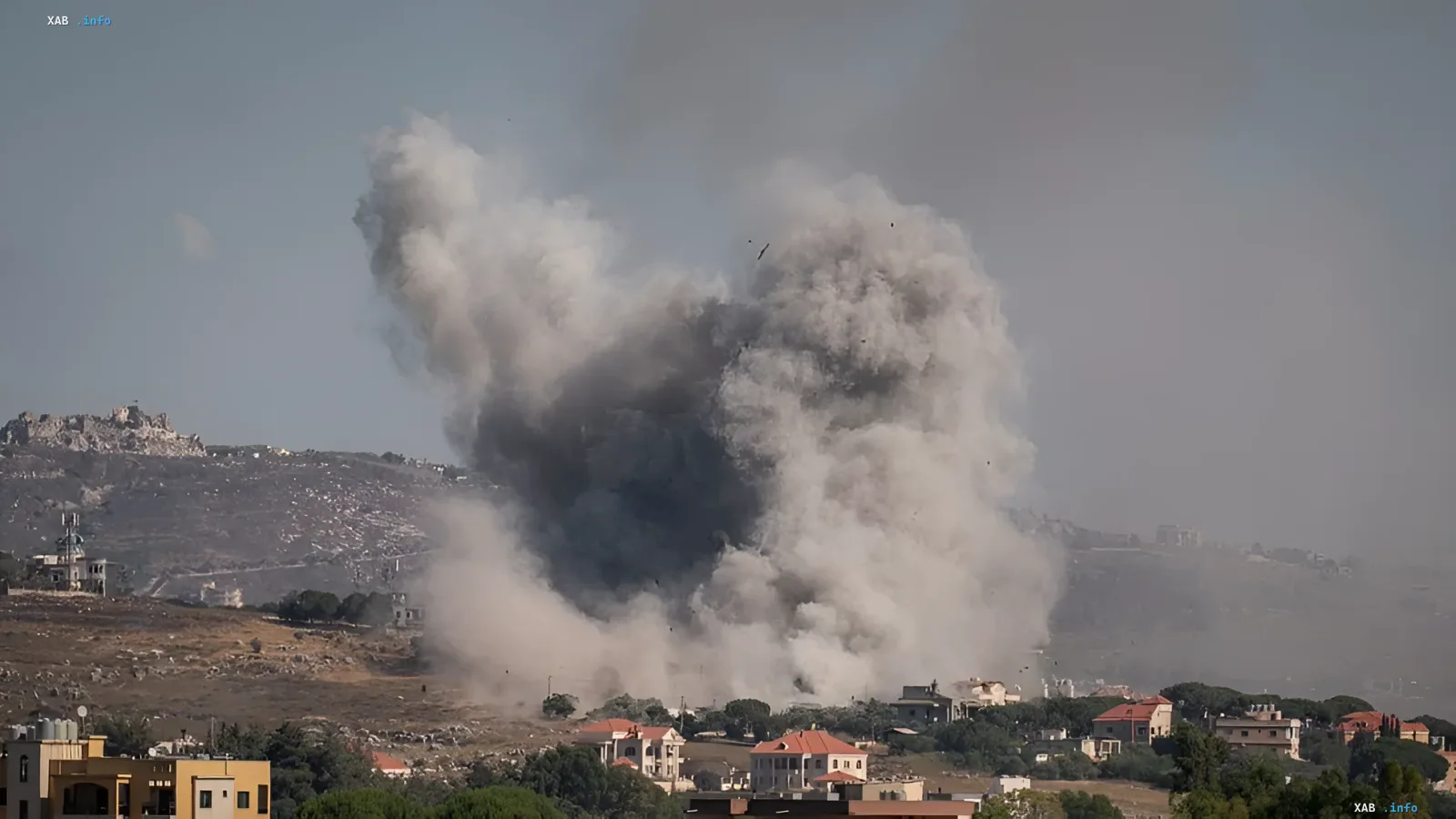 Eine starke Explosion mit Rauchsäulen über Wohngebäuden und hügeligem Gelände im Südlibanon