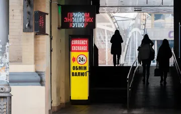 Electronic display and currency exchange sign on a street close-up with walking people