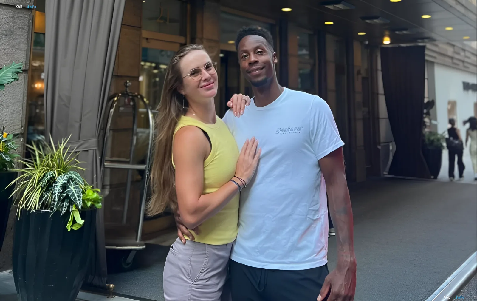 Gael Monfils und Elina Svitolina umarmen sich im Freien in der Nähe eines Hotels in Freizeitkleidung.
