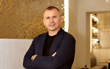 Ukrainian restaurateur Mykola Oleksiv in a dark blazer standing inside a restaurant