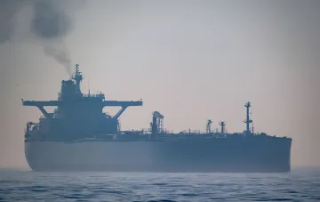Грузовой нефтяной танкер с дымом из трубы в открытом море в туманный день