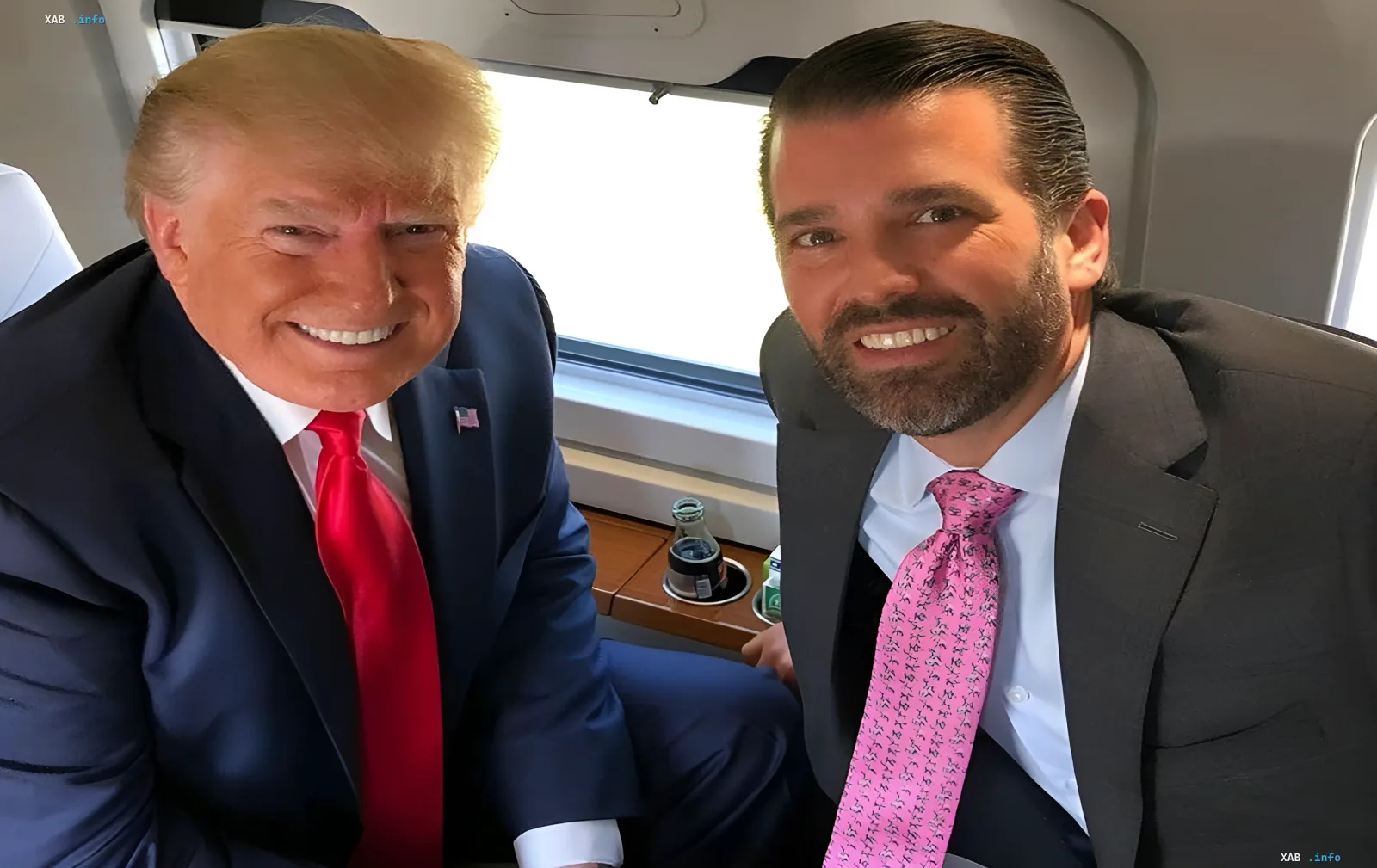 Дональд Трамп і Дональд Трамп-молодший сидять у салоні літака та посміхаються