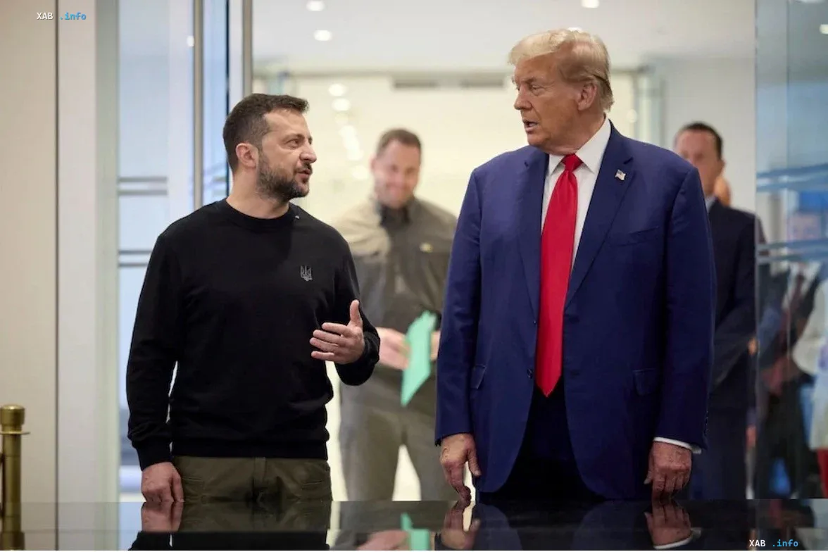 Donald Trump in a blue suit and Volodymyr Zelensky in a black sweatshirt having a conversation