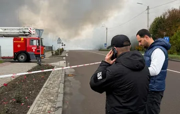 Fire engine and emergency personnel near a police tape at the strike site in Rivne