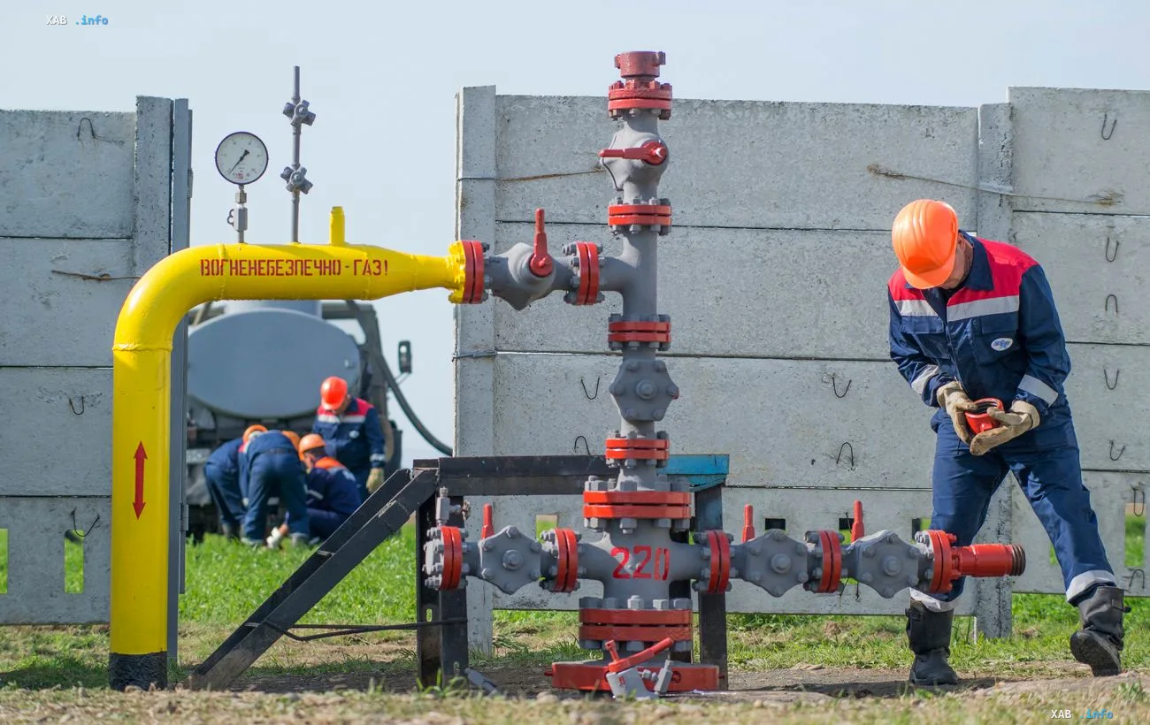 Employees of a gas production company perform maintenance on equipment at a gas distribution unit in a field
