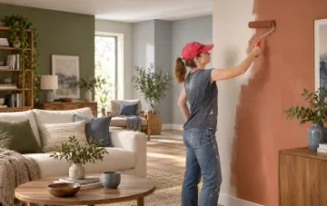 Woman in a baseball cap painting a wall in a living room with a modern natural interior palette