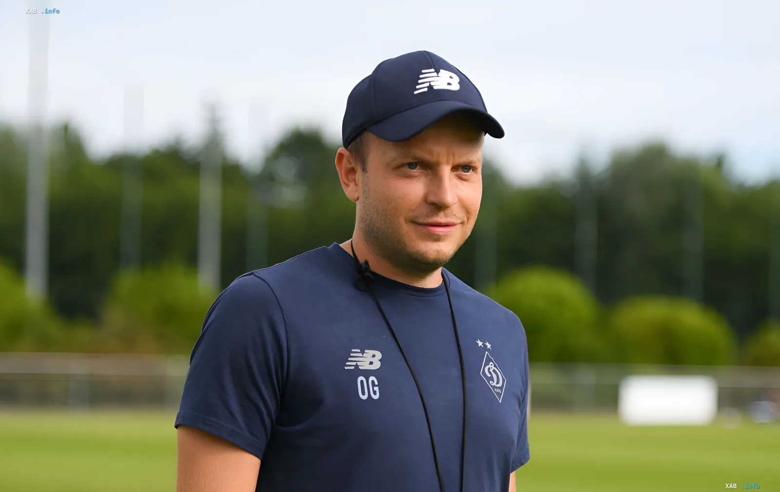 A man wearing a New Balance cap and a dark blue t-shirt with the Dynamo Kyiv crest on a football pitch