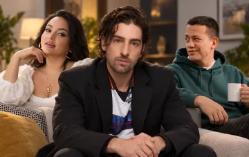 Three participants sit on a couch discussing the new season of a romantic reality show.