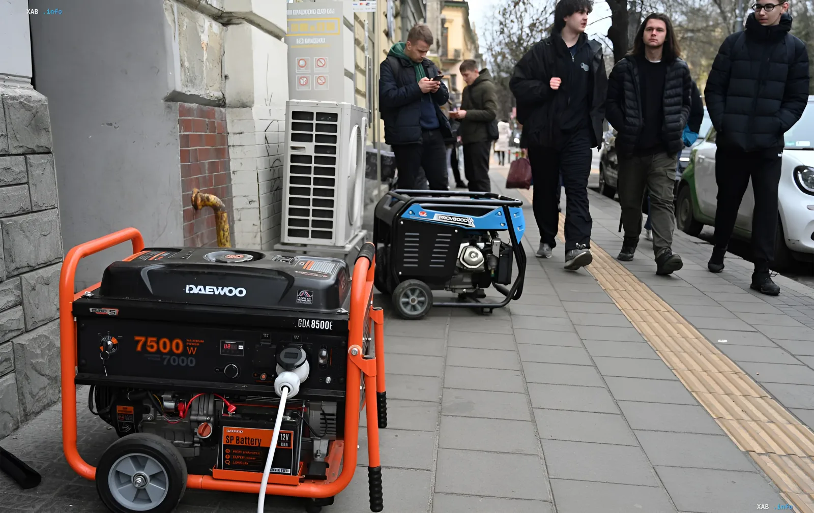 Two gasoline generators operating on a Kyiv sidewalk against the background of pedestrians