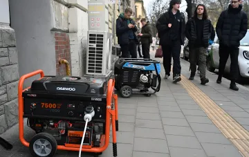 Two gasoline generators operating on a Kyiv sidewalk against the background of pedestrians