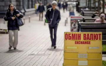 Street currency exchange sign with a yellow board against the background of pedestrians in the city
