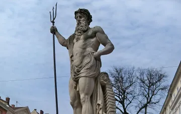 Stone statue of the god Neptune with a trident against a cloudy sky in Lviv