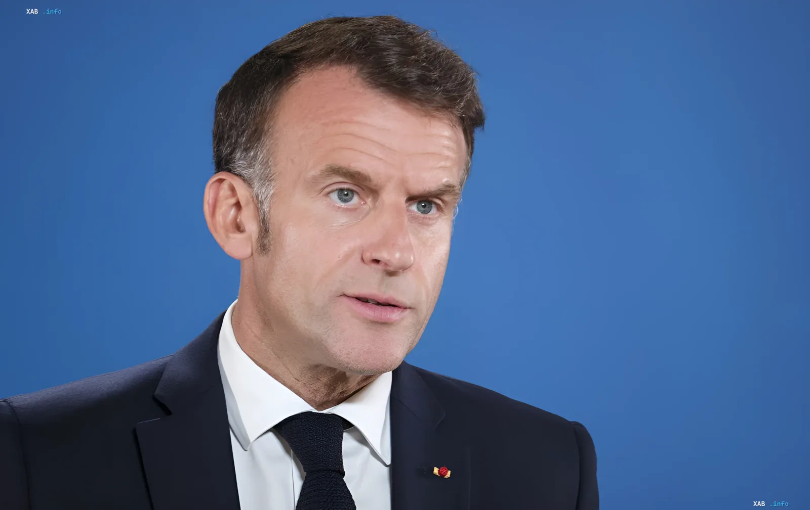 French President Emmanuel Macron speaking at a press conference against a blue background