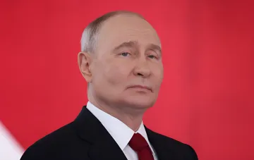 Russian President Vladimir Putin at an official event against a red background
