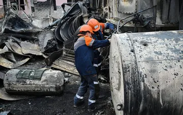 Emergency service workers in protective helmets inspect damaged industrial facilities following strikes on Ukraine's energy infrastructure.