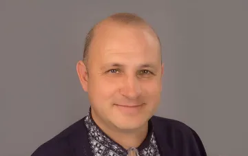 Portrait of a middle-aged Ukrainian politician wearing an embroidered shirt against a gray background